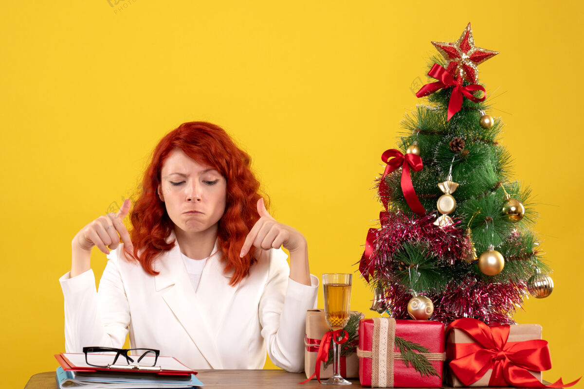 成人女工人坐在桌子后面 黄色的是礼物和文件人安排办公室