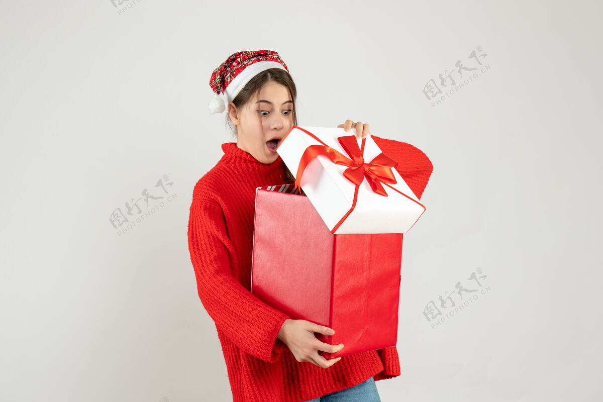 圣诞节戴着圣诞帽的大眼睛女孩打开白色圣诞礼物帽子礼物人
