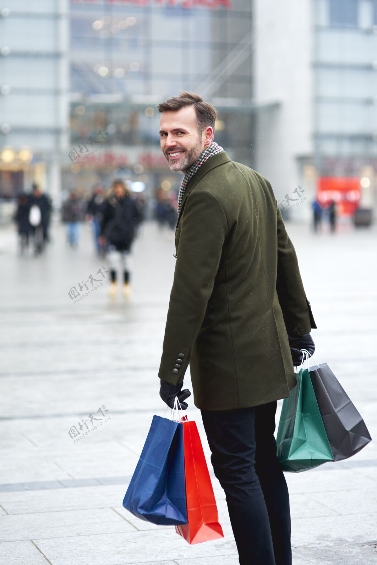 娱乐一个带着购物袋的男人走在城市的街道上购物人圣诞节