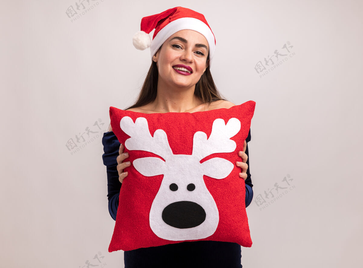 呼啦圈微笑着的年轻漂亮的女孩穿着蓝色的裙子和圣诞发箍抱着圣诞枕头隔离在白色的背景上圣诞节枕头年轻