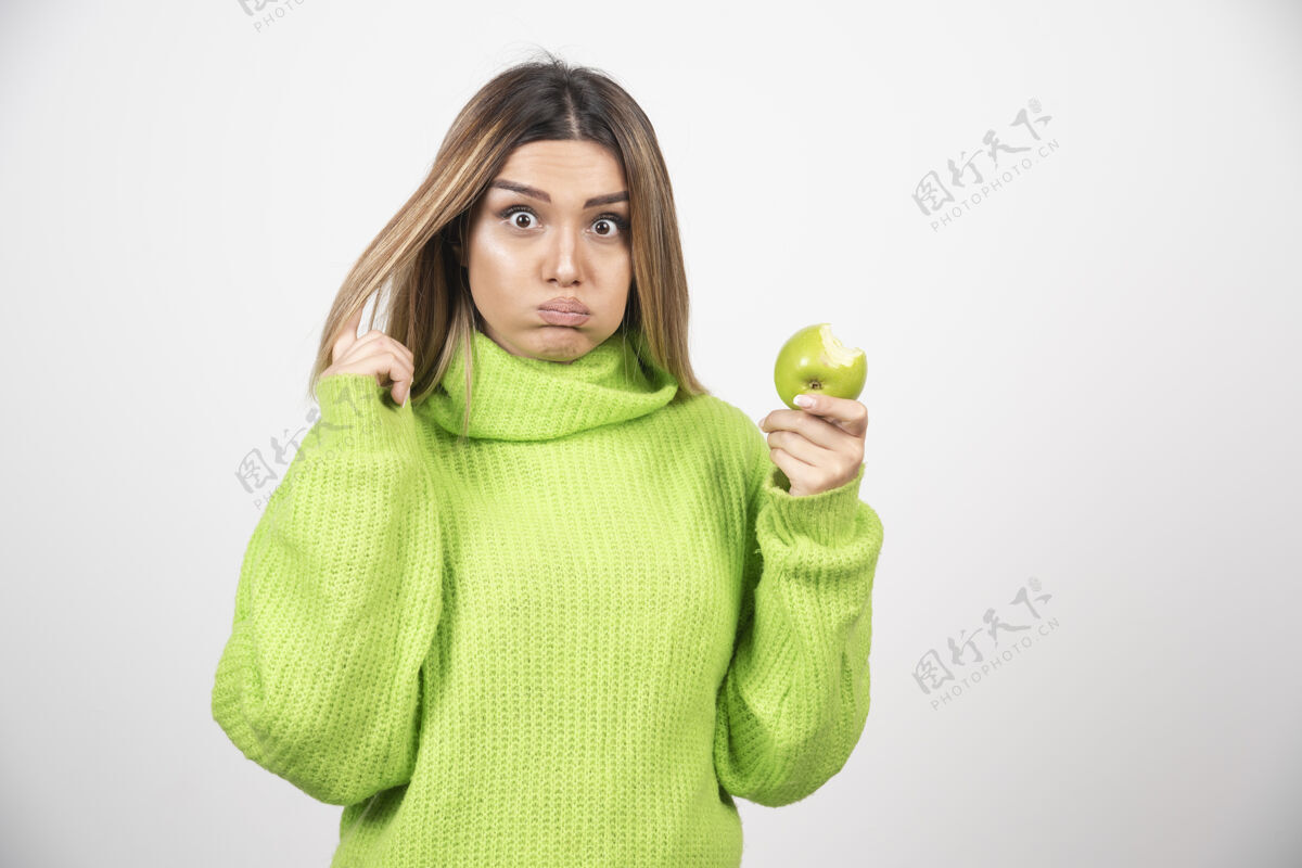 食欲穿着绿色t恤的年轻女子手里拿着一个苹果绿色女性苹果