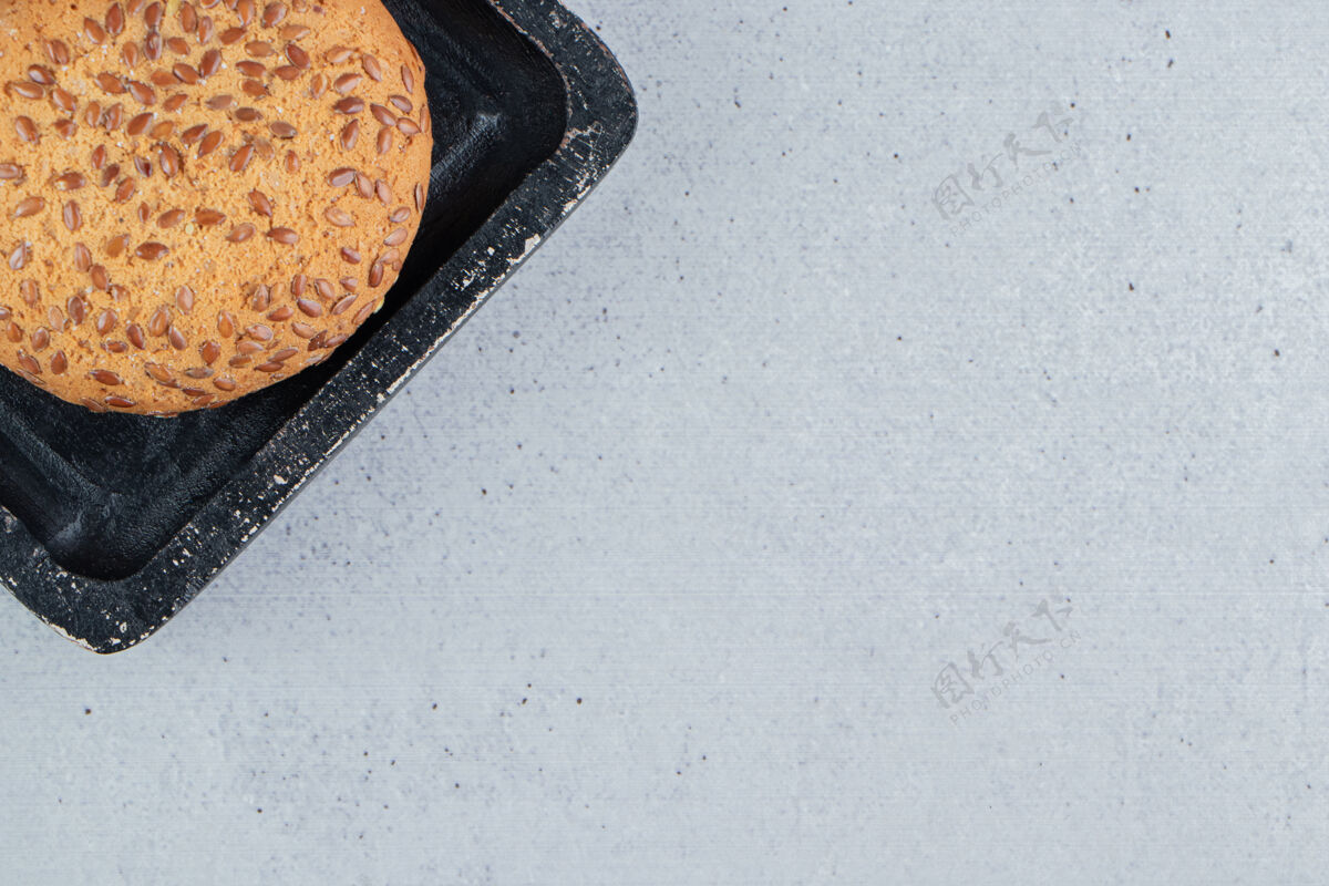 零食在大理石背景的黑色托盘上放上芝麻饼干商品涂层烘焙