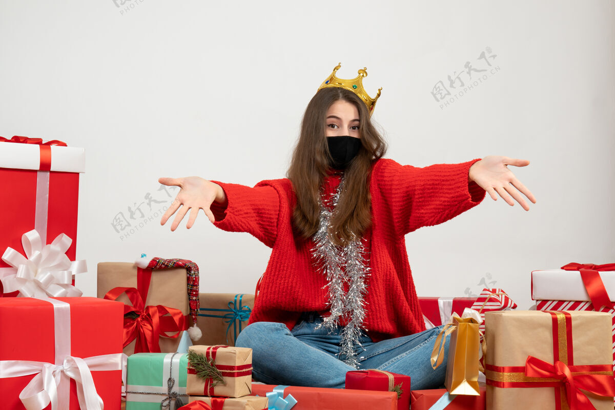 快乐穿着红色毛衣的年轻女孩张开双手围坐在礼物旁边 白色的面具上戴着黑色的面具女孩毛衣红