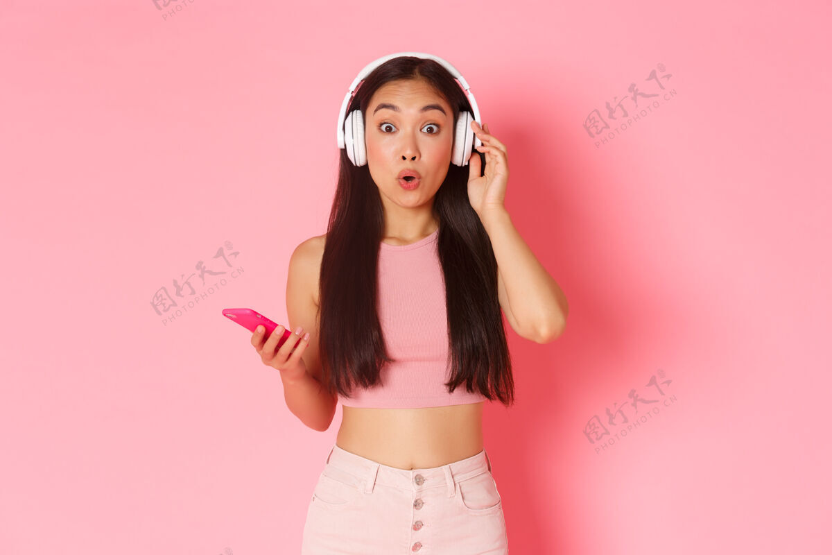 耳机一个戴着耳机听音乐的富有表情的年轻女子休闲应用程序女人
