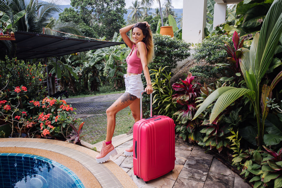 海滩在热带国家度假的高加索女人 带着大大的粉红色手提箱海景年轻等待