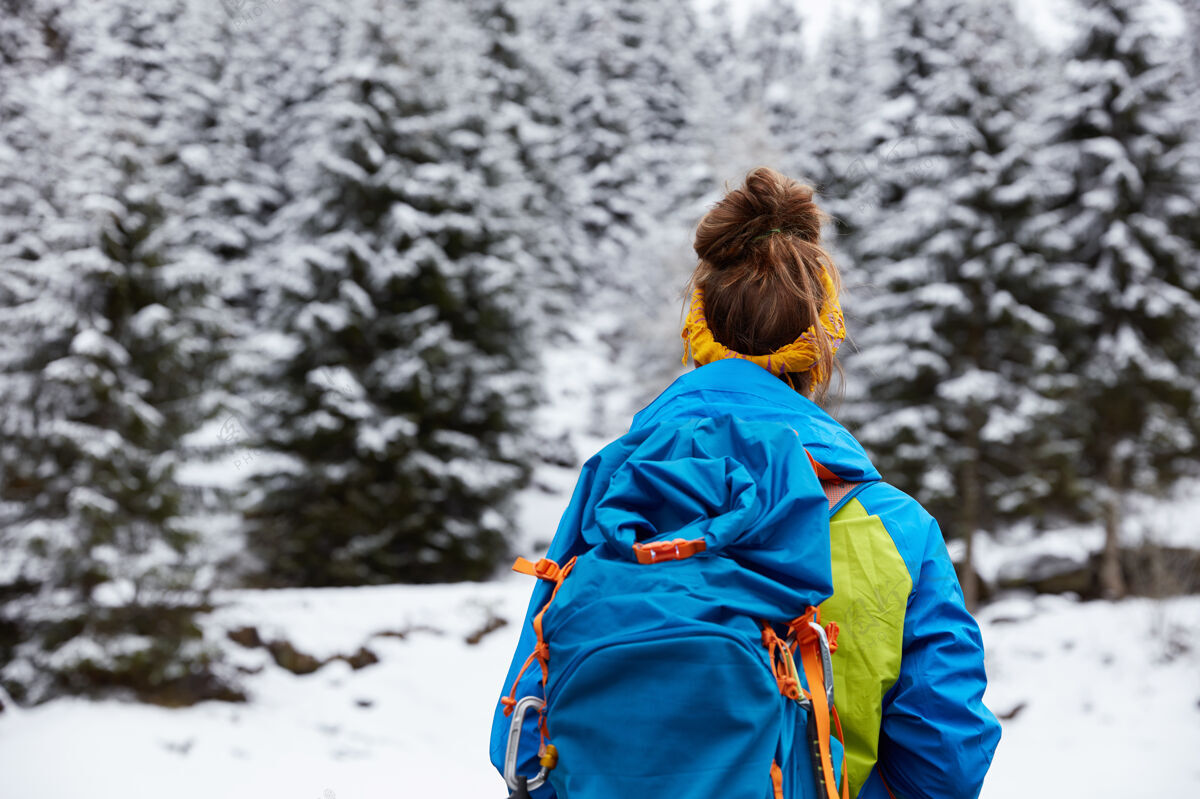 极限女游客站在雪山顶的后视图背包客登山者头带