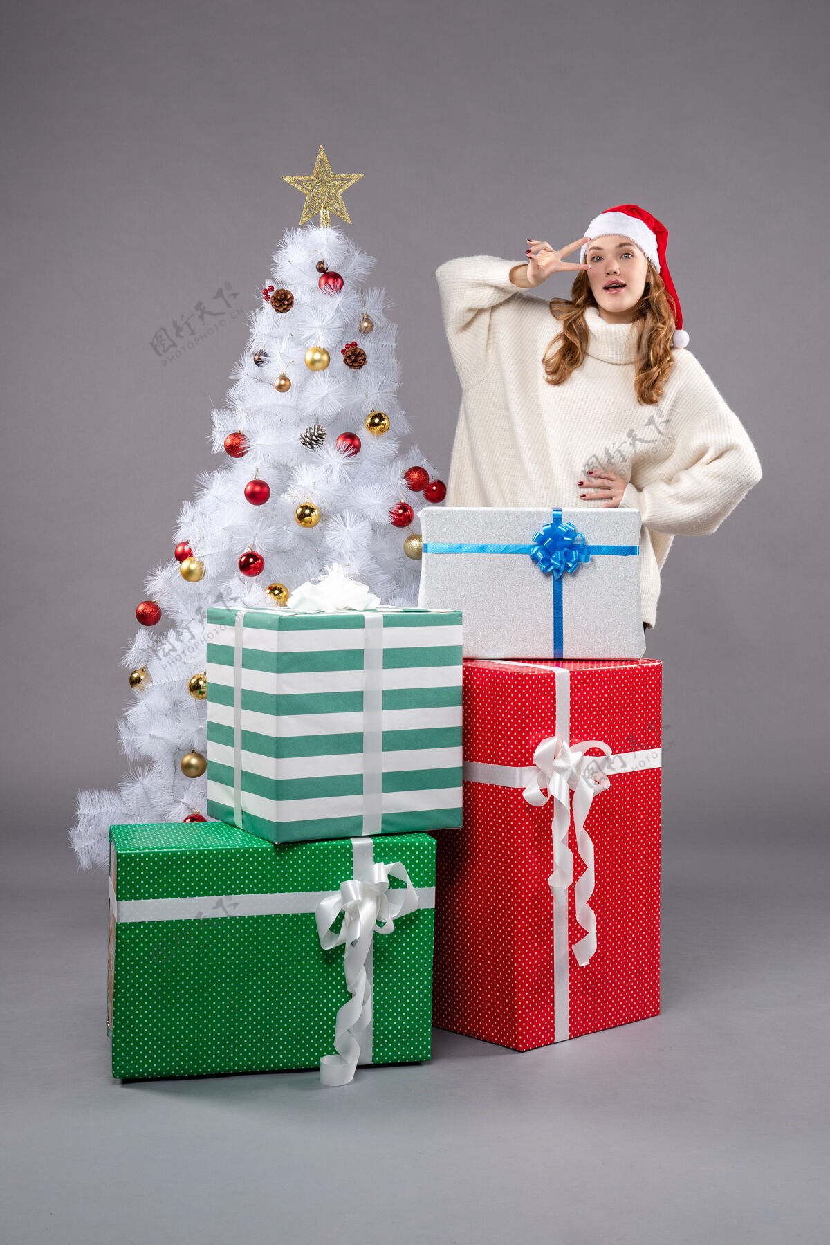 年轻年轻的女性在灰色的礼物衣服圣诞树喜剧演员