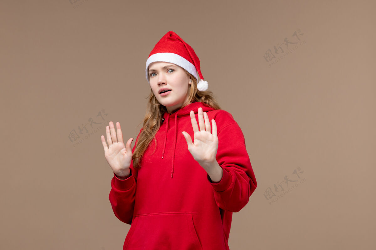 快乐前视图圣诞女孩困惑的脸上棕色背景节日圣诞节情绪人困惑可爱
