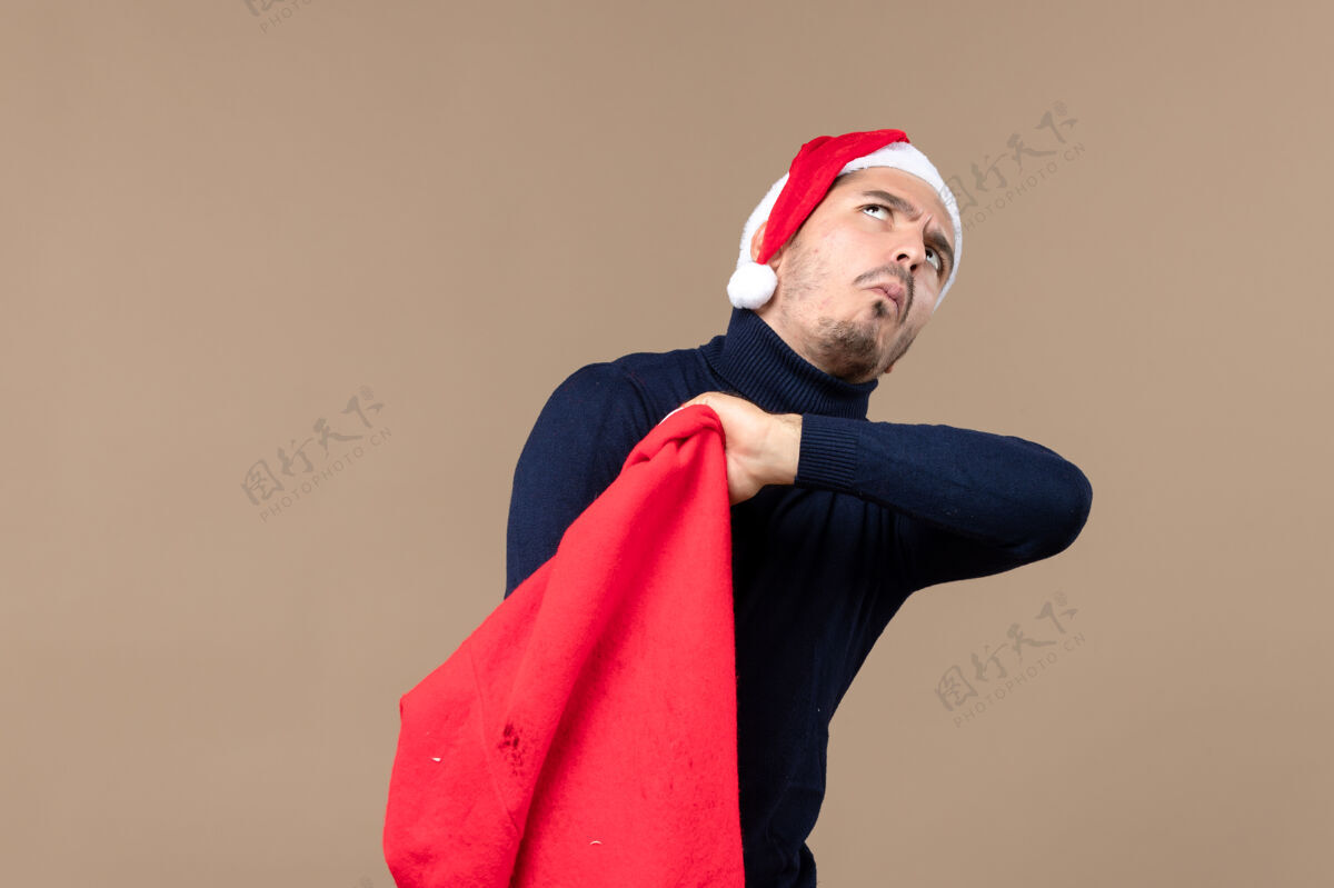成人前视图年轻男性检查棕色背景圣诞老人礼物袋脸年轻包