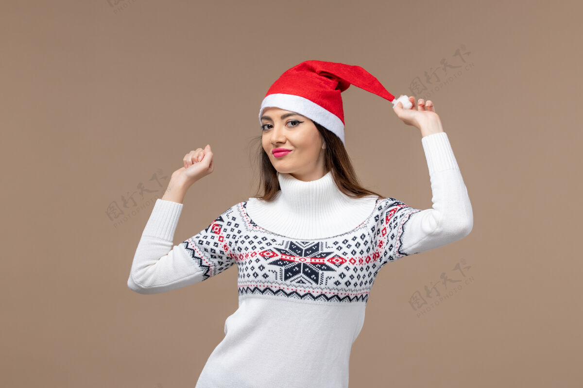 性感正面图棕色背景上戴着红色圣诞帽的年轻女性圣诞假期感慨节日可爱帽子