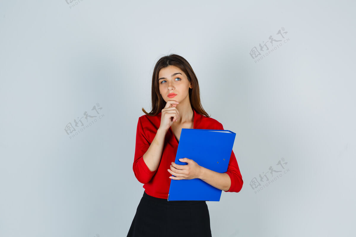 人年轻女士拿着文件夹站在思考的姿势在红色上衣女性成人漂亮