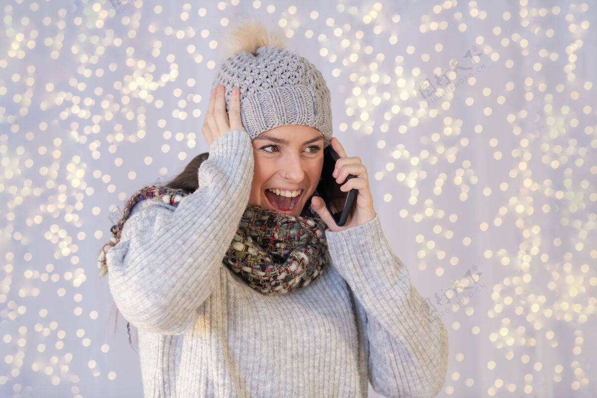 寒冷西班牙裔女子穿着暖和的毛衣 戴着帽子 讲电话时非常兴奋成人西班牙裔Bokeh