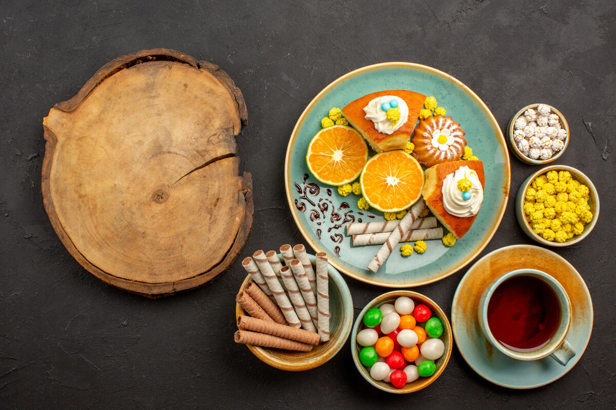 传统的顶视图美味的派片与新鲜的橘子茶和糖果在黑暗中晚餐盘子新鲜的