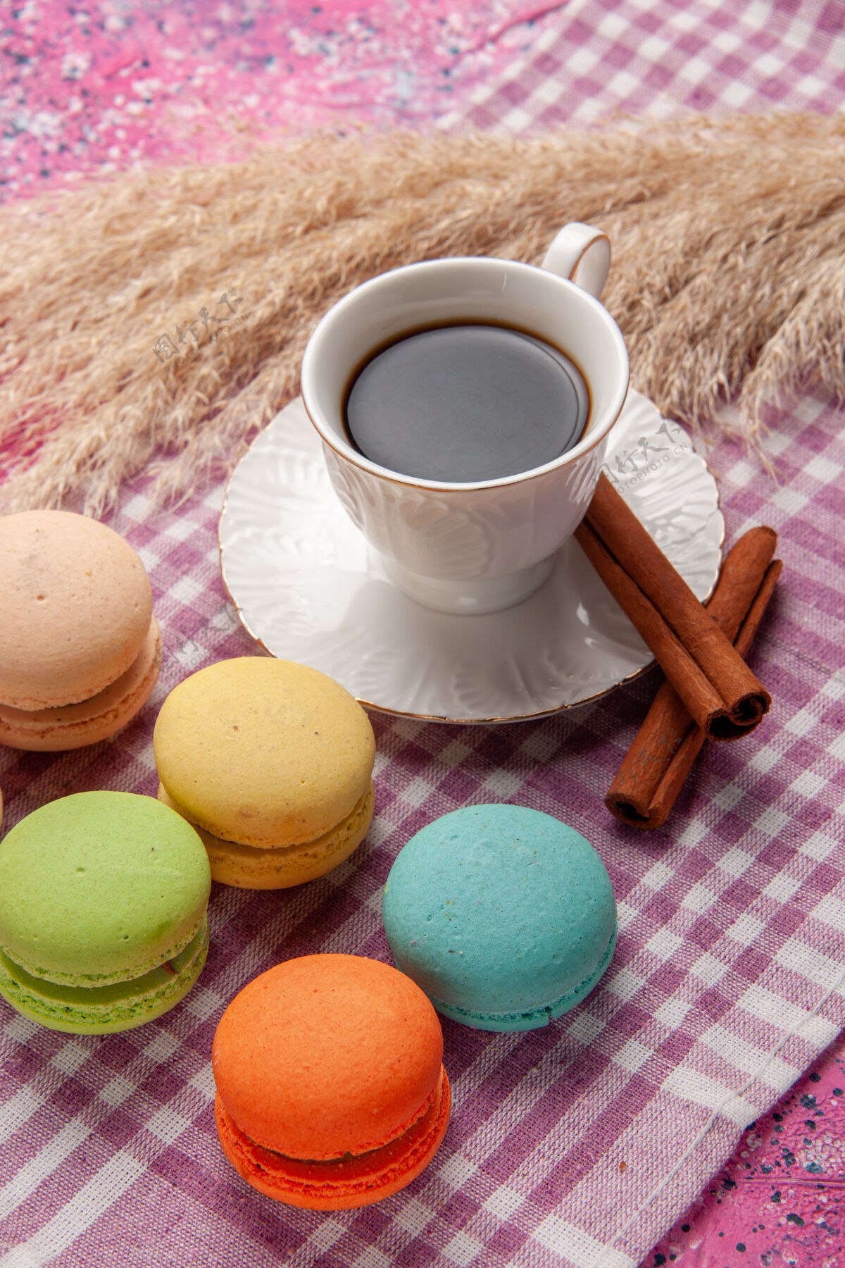 马卡龙一杯加肉桂和法式马卡龙的茶 放在粉红色的桌上蛋糕 饼干 甜甜的糖鸡蛋生的风景