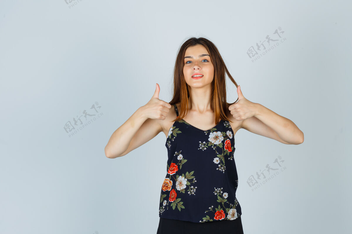 欢快穿着衬衫的年轻漂亮的女性 竖起大拇指 看起来很快乐年轻拇指休闲