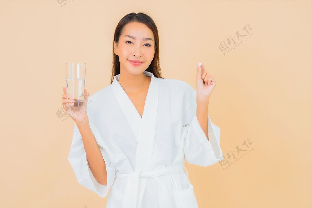 胶囊一幅美丽的亚洲年轻女子的画像 米色的水杯和药丸女性感冒抗生素