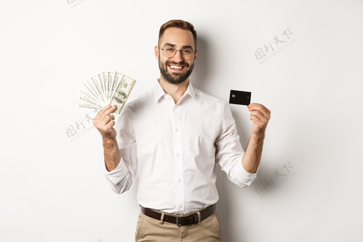 雇员英俊的商人展示信用卡和钞票 微笑着高兴 站着自信男人经理