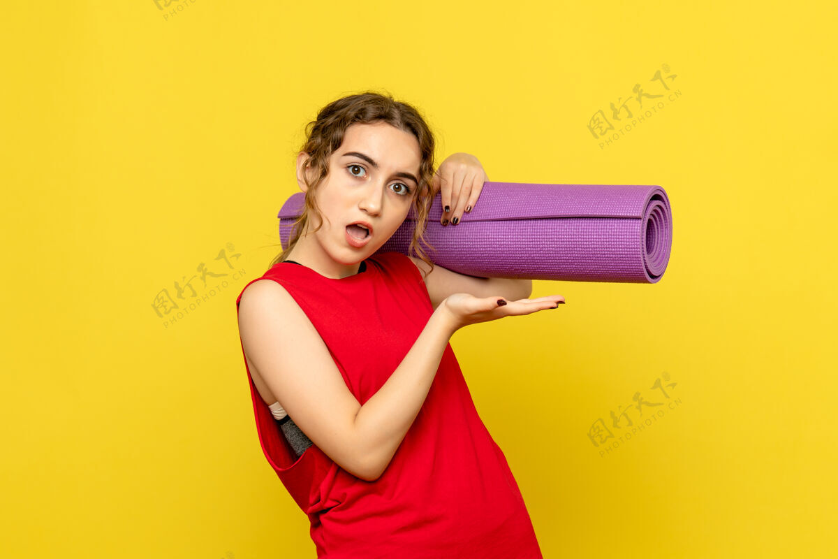 烘干机黄色墙壁上拿着紫色地毯的年轻女子的正视图运动地毯模特