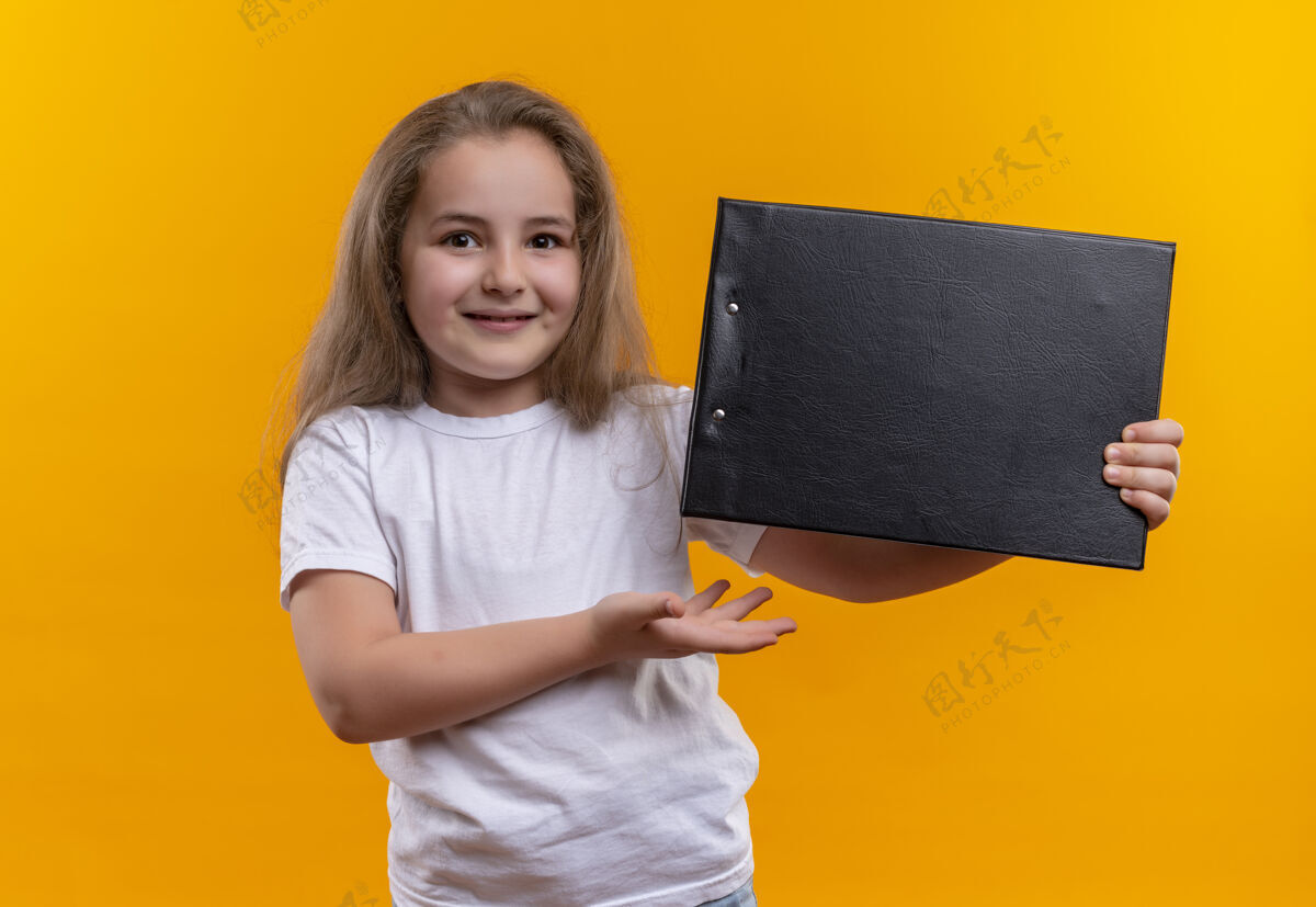 学校微笑的小女孩穿着白色t恤拿着剪贴板在孤立的橙色背景微笑白色穿着