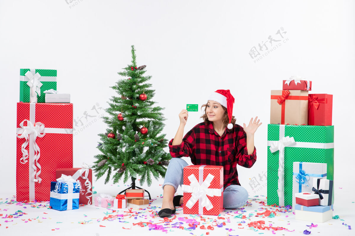 快乐正面图：年轻女子围坐在白墙上 手里拿着绿色的银行卡快乐节日圣诞节