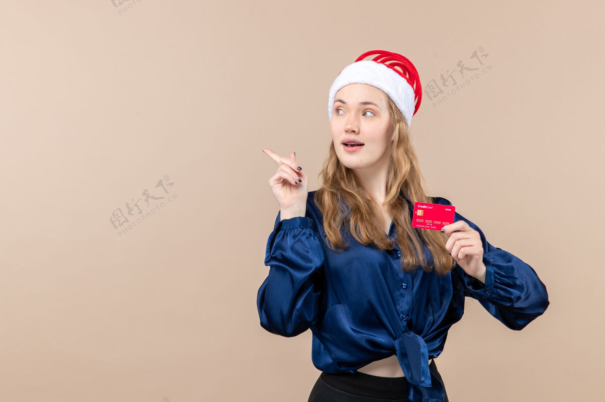 银行正面图年轻女性手持红色银行卡上粉红色背景钱假日照片新年圣诞情绪自由的地方女举行钱