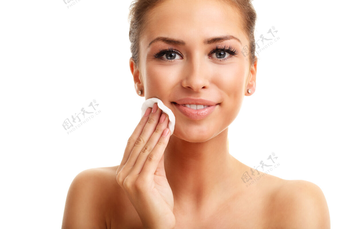 护理成年女子对着镜头微笑 在白色的隔离背景下使用化妆棉自然脸手