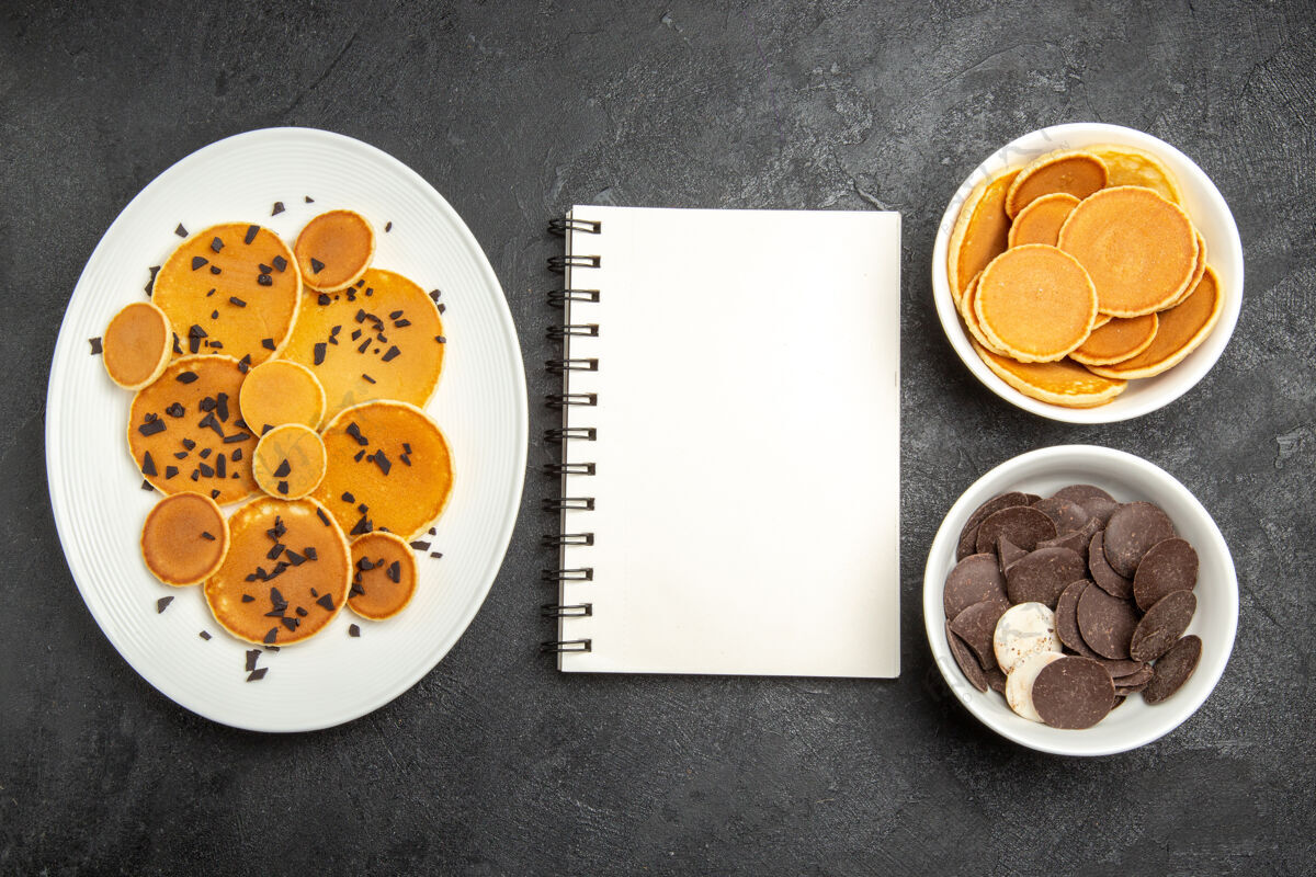 薄煎饼在黑暗的背景下 俯瞰美味的薄饼和巧克力片和饼干橘子饼干薯条