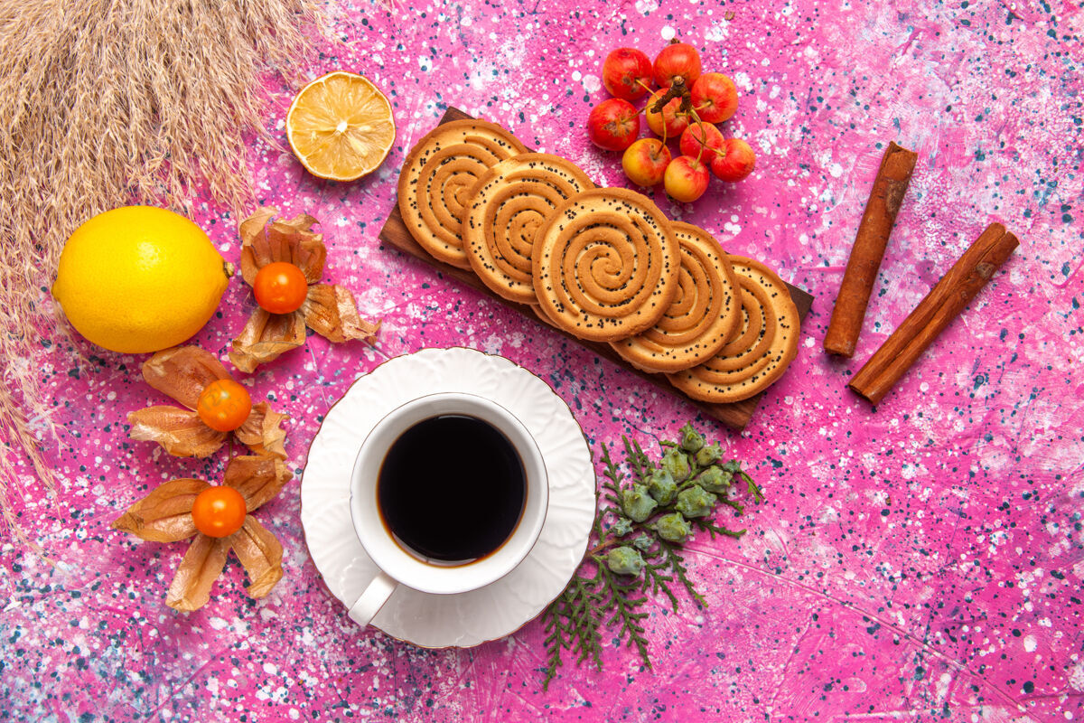 食物浅粉色表面的柠檬茶和肉桂小饼干俯视图生的咖啡饼干