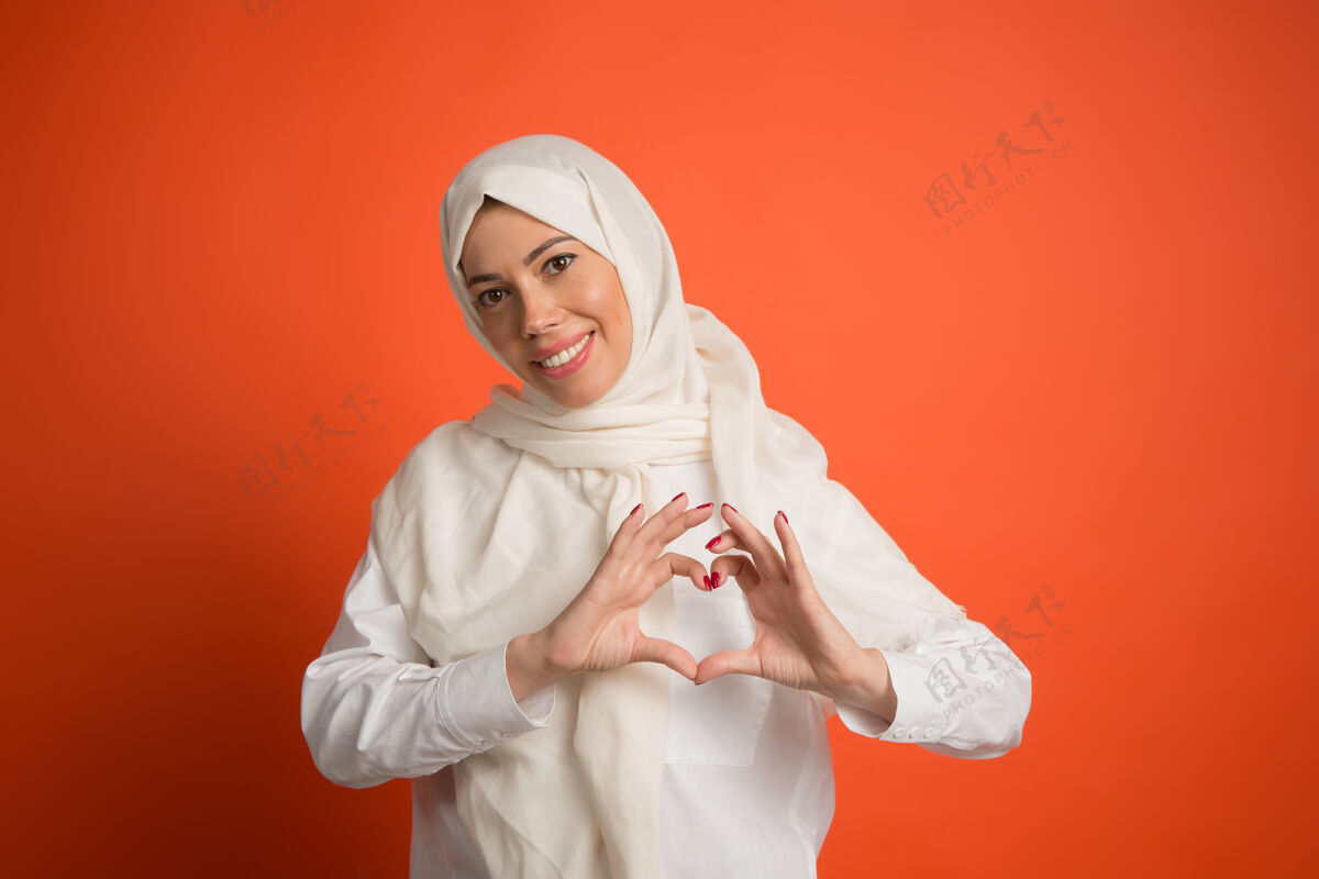 围巾戴着头巾的快乐阿拉伯女人微笑女孩的肖像 在红色工作室背景下摆姿势年轻感性的女人人类情感 面部表情概念正面视图宗教服装阿拉伯语