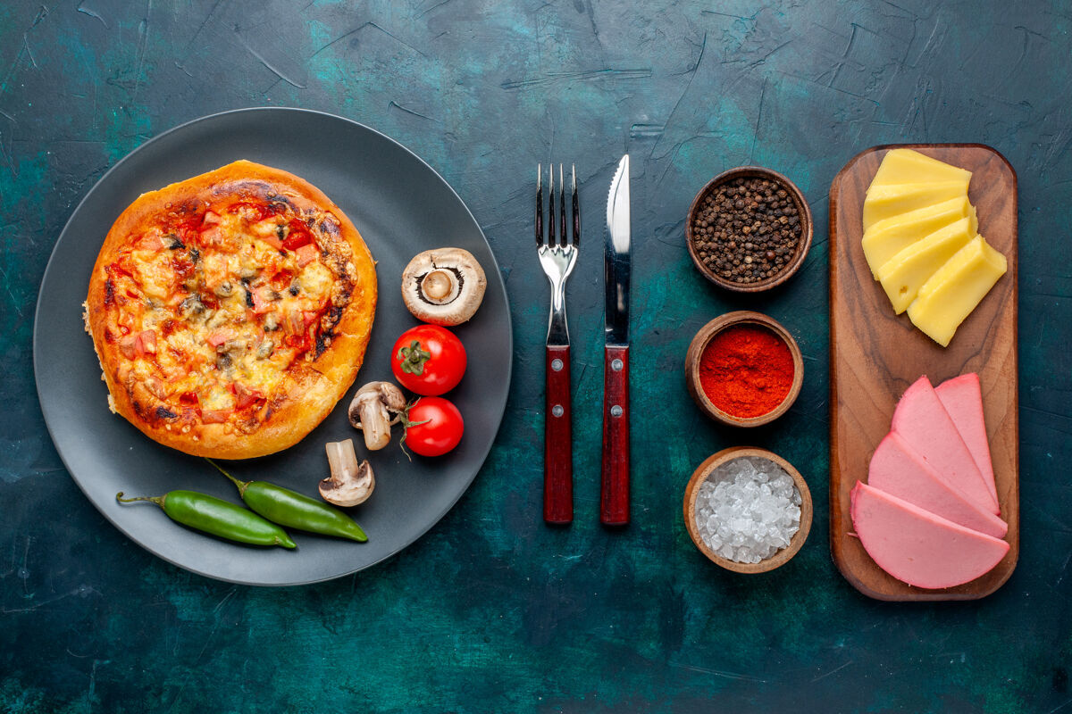 奶酪小芝士比萨饼的俯视图 深蓝色表面有调味品 蔬菜和奶酪晚餐生的晚餐