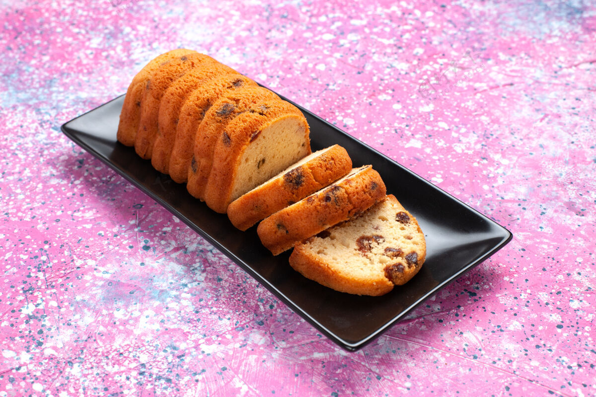 派在粉红色的桌子上切的美味蛋糕切片棕色饼干