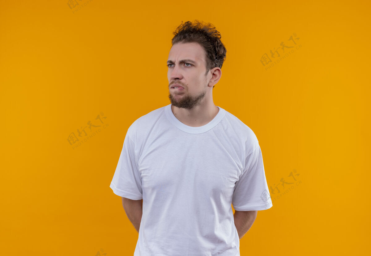 T恤看着身边穿着白色t恤的年轻人咬着嘴唇孤立的橙色背景橙色穿嘴唇