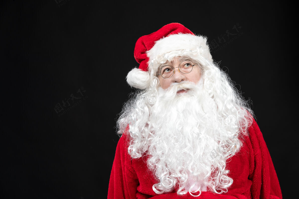 节日圣诞老人穿着经典的红色套装 黑墙上留着白胡子的正面图圣诞快乐西装
