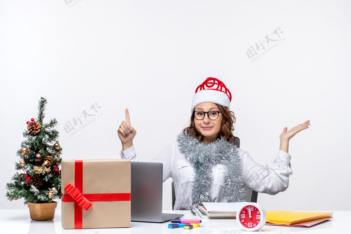桌子正面图年轻女工坐在她工作的地方前 在白色的地板上办公桌上工作 工作 圣诞节的女人前面办公室坐着