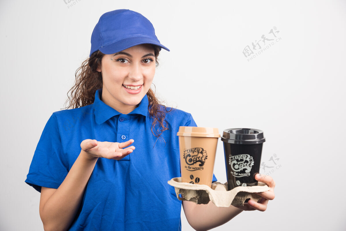 年轻人穿着蓝色制服的女人在两杯咖啡上展示白色背景成人工人马克杯