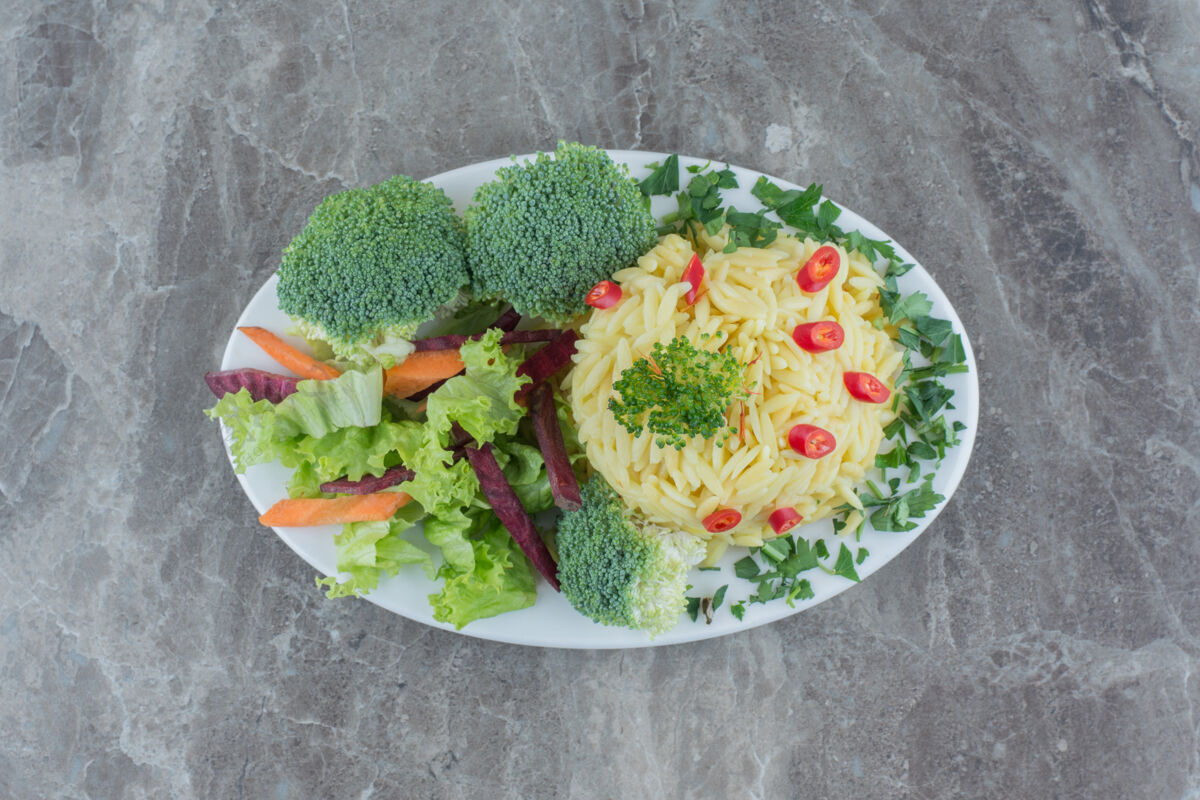 花椰菜用切碎的胡椒粉 卷心菜 青菜 胡萝卜和花椰菜片装饰在大理石盘上的皮劳蔬菜胡萝卜菜肴
