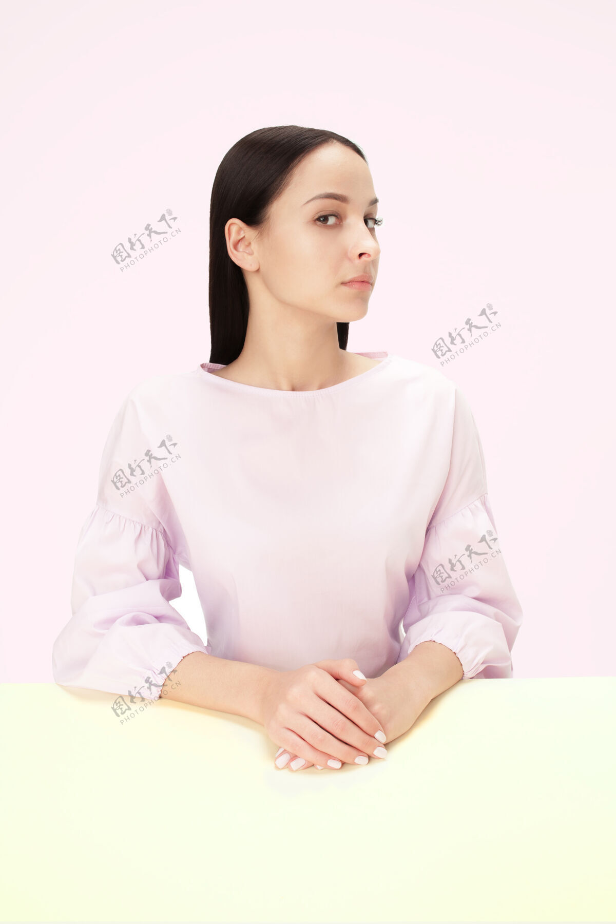 女性正经的女商人坐在粉色画室背景的桌子旁这是一幅极简风格的肖像画经理长严肃