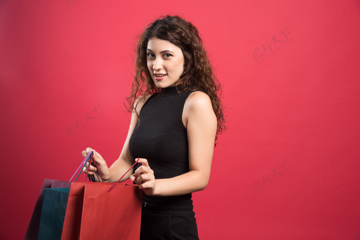 购买在红色背景上展示新买衣服的女士高质量照片购物服装快乐购物
