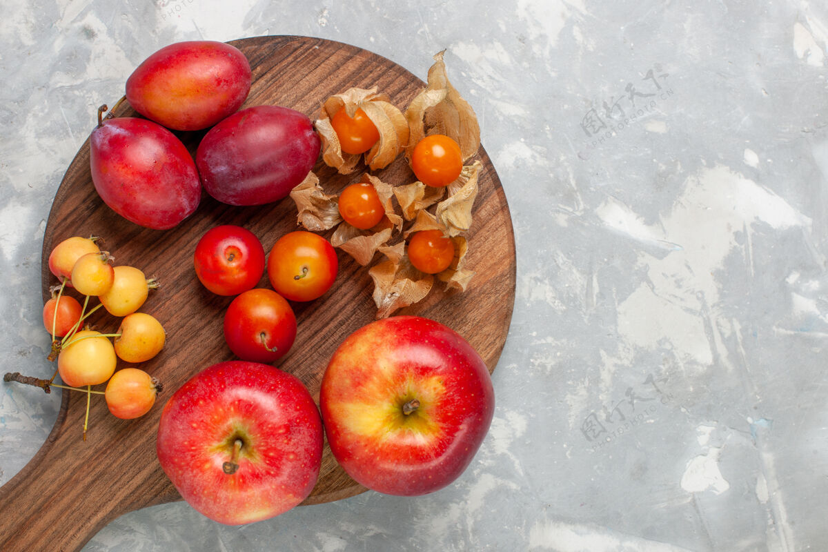 苹果顶视图不同形状的李子酸和新鲜水果与樱桃放在浅白的桌子上樱桃苹果不同