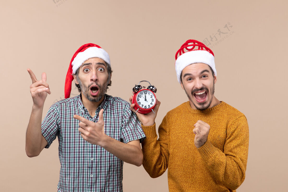 消费品正面图两个男人一个困惑 另一个拿着一个闹钟 在米色孤立的背景上快乐的脸男手持脸