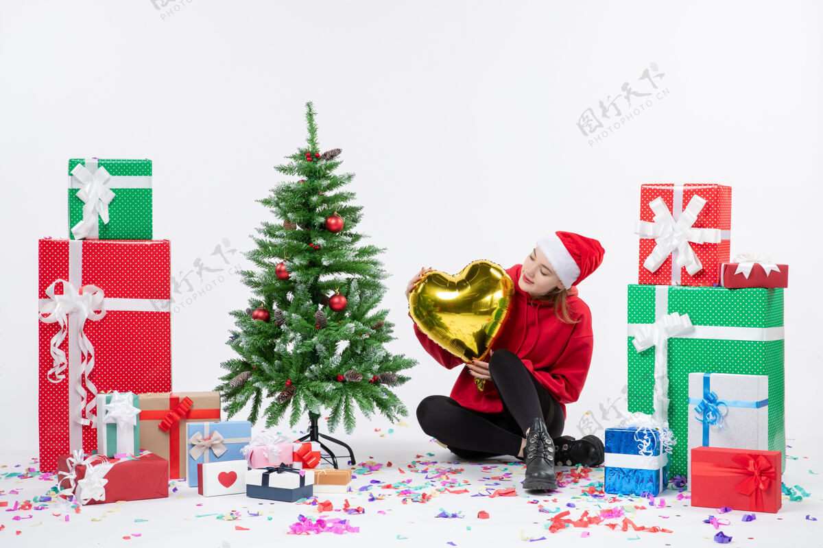 圣诞树正面图：年轻女子围坐在白色墙壁上 手持金心形礼物装饰礼物情绪