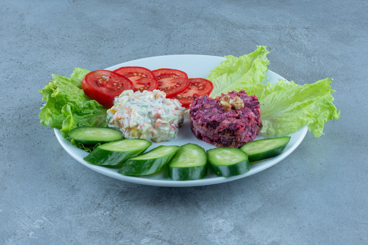晚餐用黄瓜 西红柿和莴苣叶装饰在大理石上的沙拉蔬菜美味开胃菜