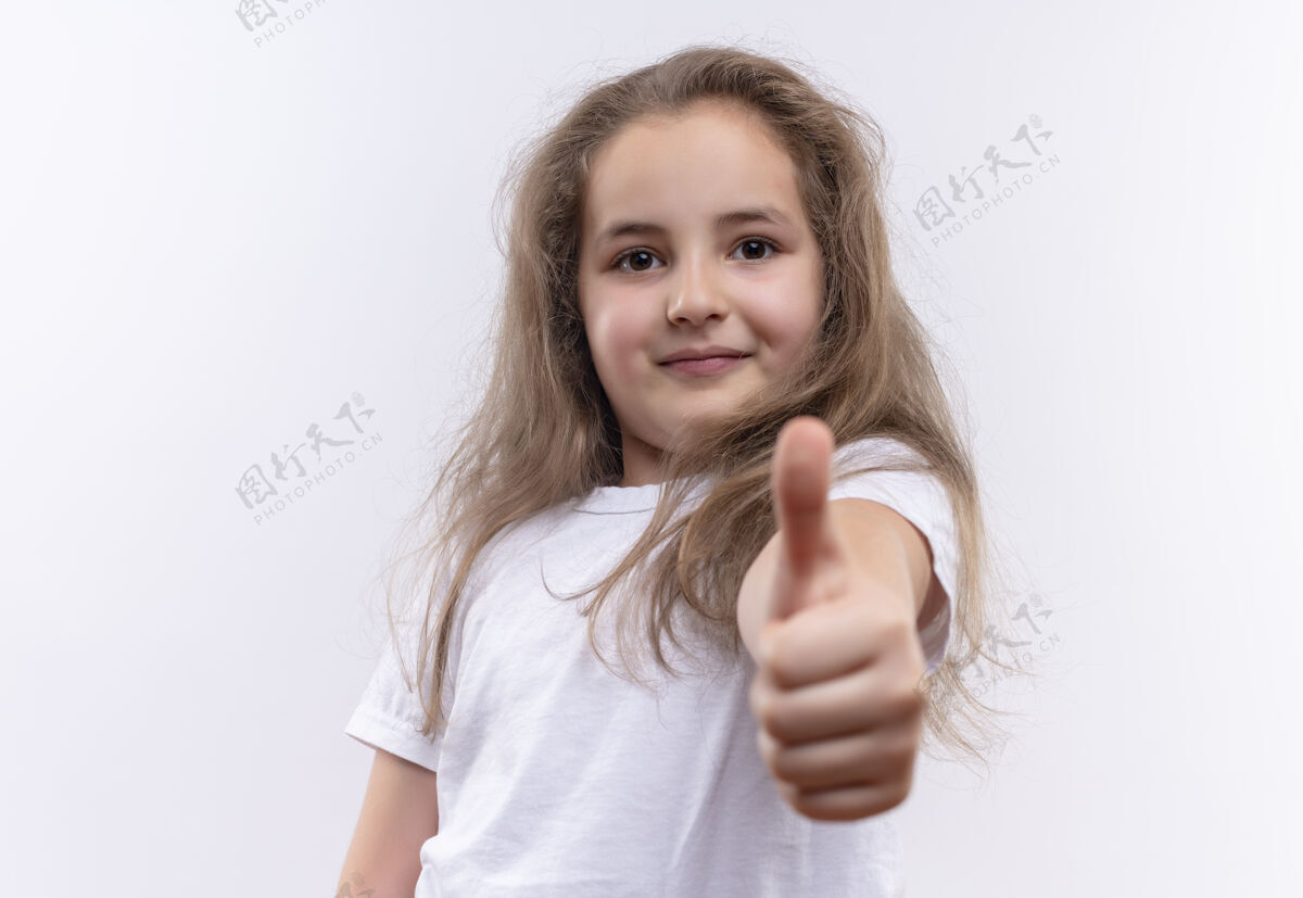 向上微笑着的小女孩穿着白色t恤 在孤立的白色背景上竖起大拇指小女孩穿着