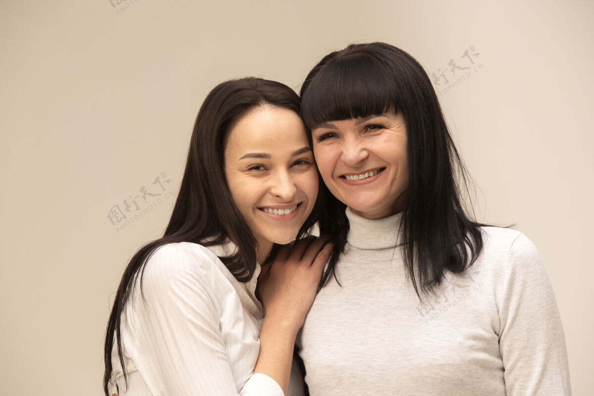 老年一个快乐的母亲和女儿在灰色背景工作室的肖像人类积极的情绪和面部表情的概念年轻面部成人
