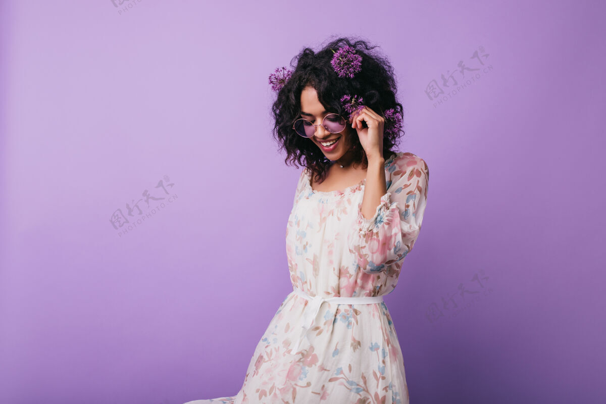 美国黑人迷人的非洲女孩 穿着花朵图案的裙子头发上扎着蒜头的无忧无虑的黑人女士的肖像乐趣休息开花