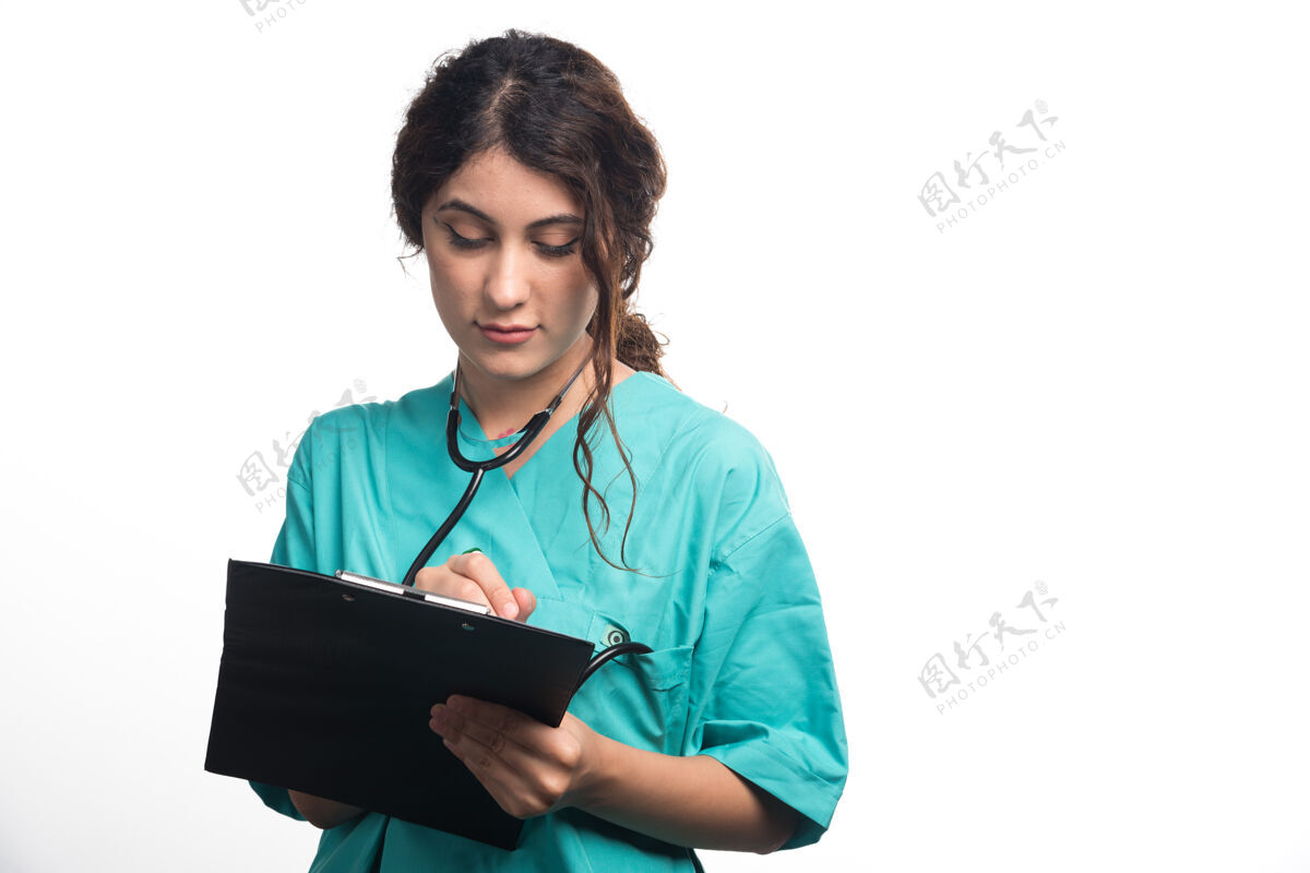 检查带听诊器的女医生在白色背景的剪贴板上写东西高质量的照片制服向上药物