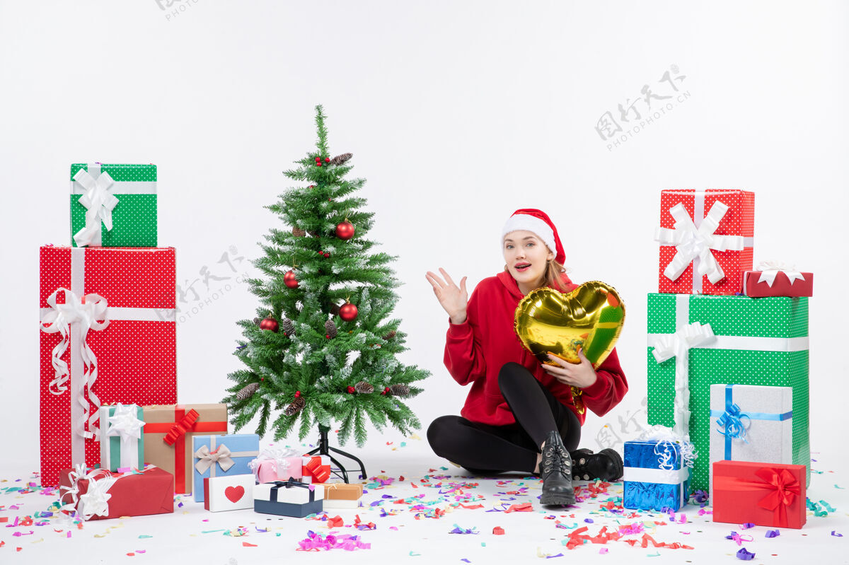 礼物正面图：年轻女子围坐在白色墙壁上 手持金心形礼物抱着冬天坐着