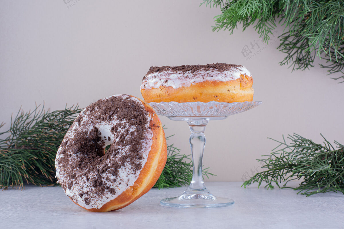 小吃甜甜圈靠在白色背景的玻璃架上烘焙有光泽树枝