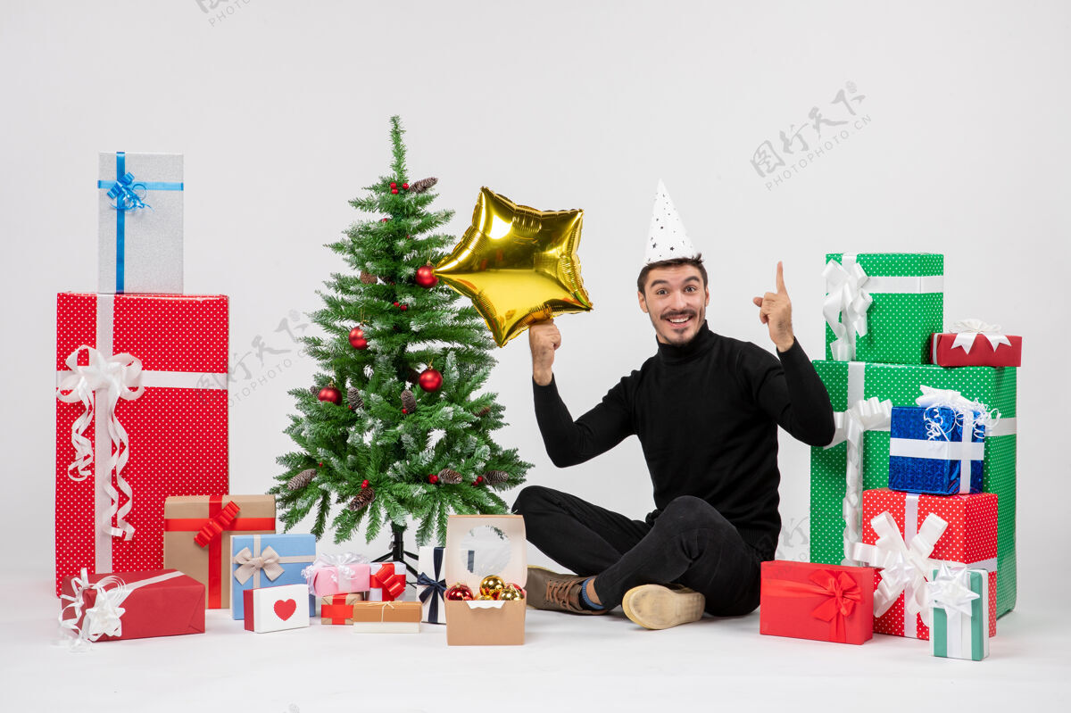 礼物年轻人围坐在礼物旁边 拿着金星在白墙上礼物星星圣诞快乐