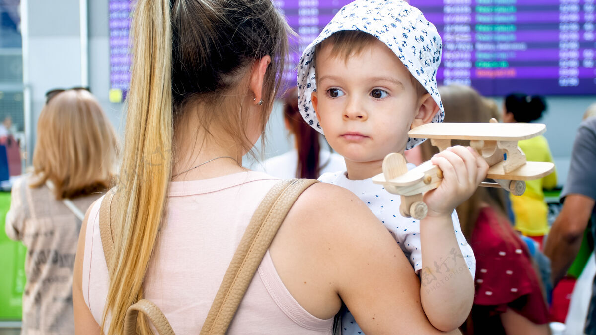 脸悲伤的小男孩抱着玩具飞机在机场拥抱母亲的画像婴儿休闲欢乐